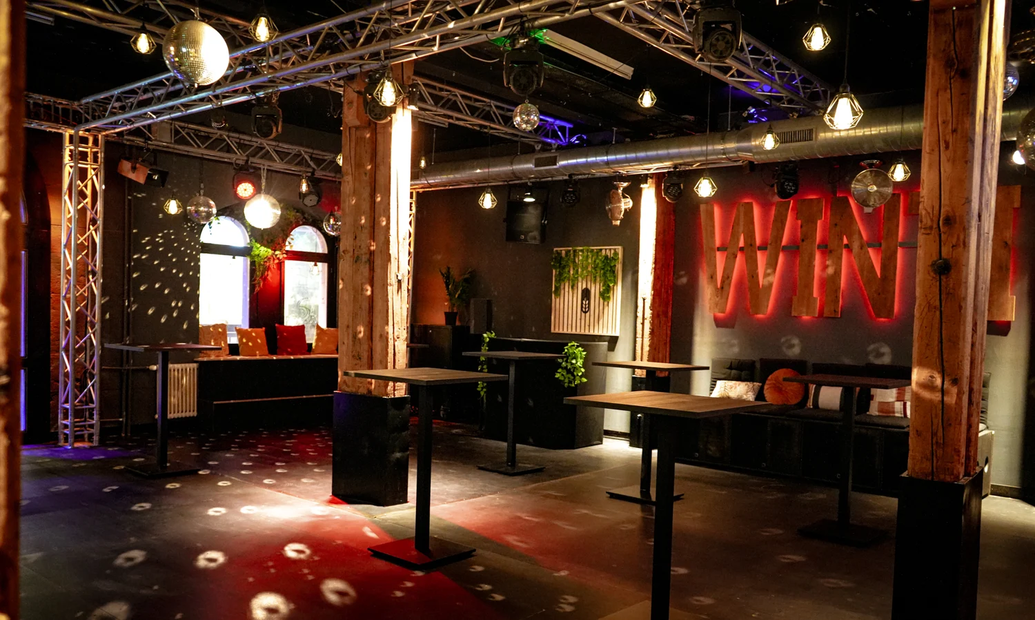 Partybereich mit farbigem Licht und Holztischen