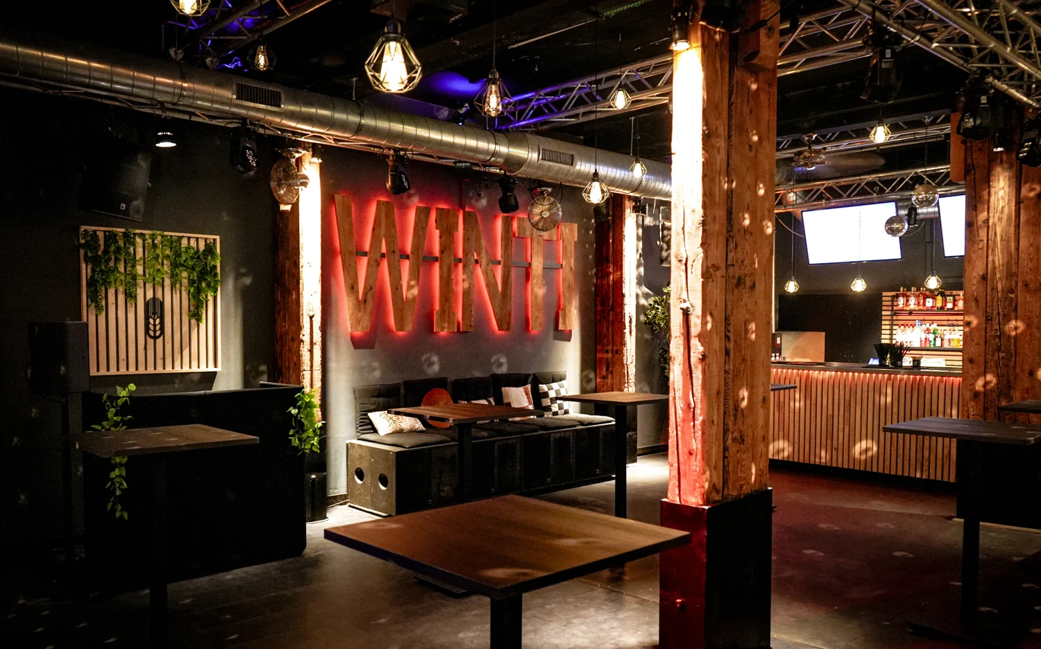 Partybereich mit eigener Bar, Holztischen und stimmungsvoller Beleuchtung